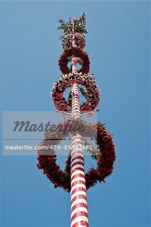 Looking up a red striped maypole in austria