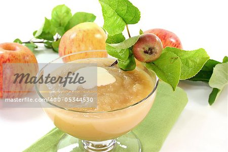 Applesauce with vanilla sauce and fresh apple with leaves on a white background