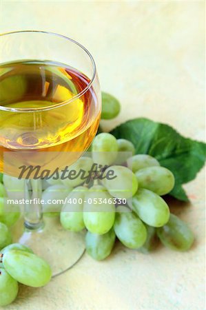glass of white wine and a branch of green grapes