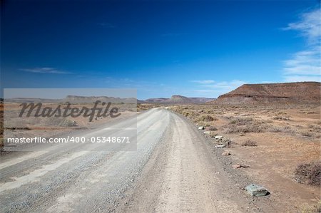 Dry landscape in South Africa with a lonely road or highway with a vision and a clear blue sky - horizontal