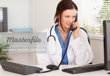 A female doctor is telephoning in her office