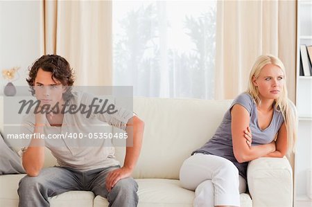 Sorrowful couple sitting on a couch looking away from the camera