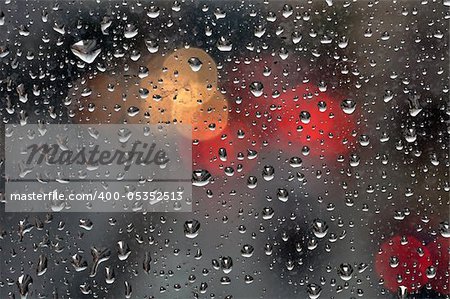 Raindrops on glass surface and blurry abstract city lights. Background texture.