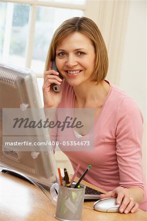 Woman Using Computer And Talking On Phone