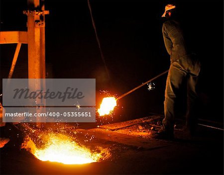 A man working in a cast iron factory close to the melting pit of the foundry
