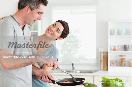 Woman smiling at her pan-holding husband in a kitchen