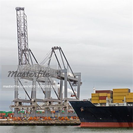 Huge container vessel, moored off at an industrial harbor facility, ready to be unloaded