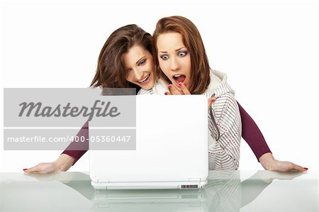 Two beautiful girls sitting behind a laptop very surprised