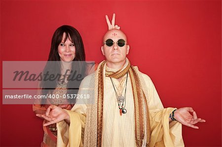 Woman with peace sign or bunny ears over meditating Guru's head