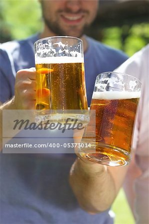 Two men with glasses of the light beer in the garden