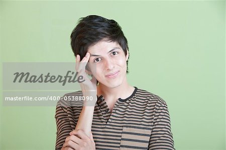 Young Latino man holds his head over green background