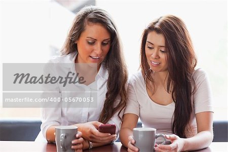 Friends looking at a smartphone while having a coffee