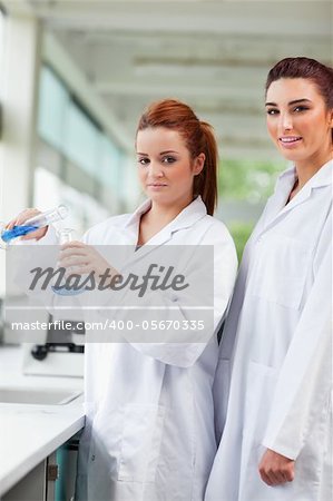 Portrait of scientists pouring blue liquid in an Erlenmeyer flask in a laboratory