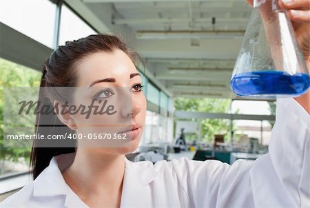 Brunette looking at an Erlenmeyer flask in a laboratory