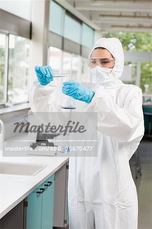 Portrait of a protected female scientist pouring liquid in a Erlenmeyer flask in a laboratory