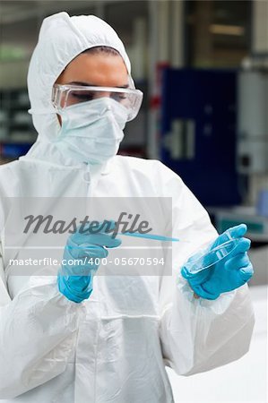 Portrait of a protected science student dropping blue liquid in a Petri dish in a laboratory