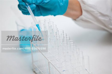 Protected hand dropping liquid in a test tube in a laboratory