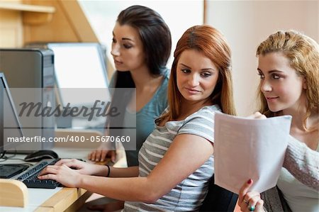 Smiling student showing her notes to her classmate in an IT room