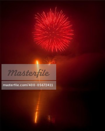 Colorful fireworks on black sky background with water reflections