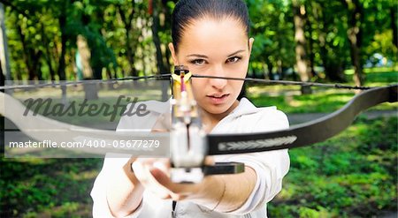 beautiful young girl with arbalest on the wood background