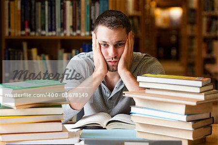 Depressed student having a lot to read looking at the camera