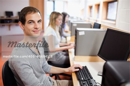 Portrait of a male student posing with a computer in an IT room