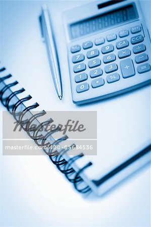 Angled notebook with pencil and pocket calculator on a white background