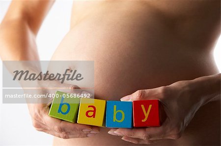 Pregnant Woman Holding Blocks Spelling "Baby"