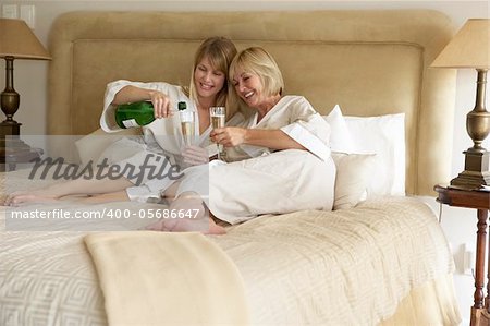Two Women Enjoying Champagne In Bedroom