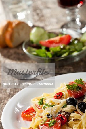 fresh pasta with tomatos and olives on a plate
