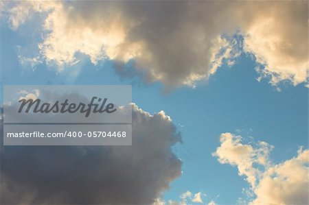 Cloudscape, dark gray and light yellowish clouds on the blue sky