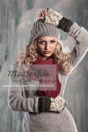 pretty young girl with curly blond hair in winter dress with hat and scarf playing and smiling to the camera