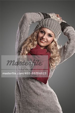 beautiful blonde curly girl in a winter fashion portrait wearing grey wool and a red scarf