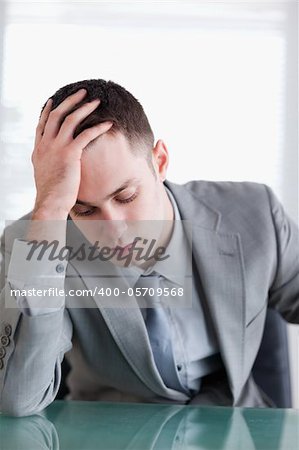 Close up of disappointed young businessman sitting behind a table