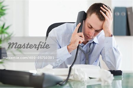 Frustrated businessman looking at an invoice while on the phone