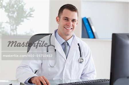 Smiling young doctor on his computer