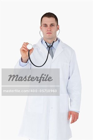 Serious looking doctor using stethoscope on white background