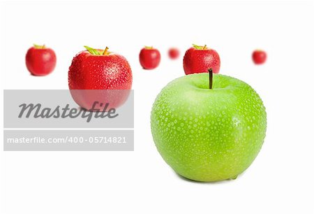 Green apple in front of red apples on white background