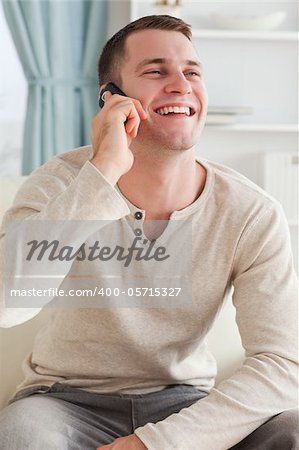 Portrait of a laughing man making a phone call while sitting on a sofa against a white background