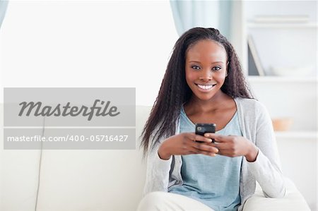 Smiling woman in living room with her phone