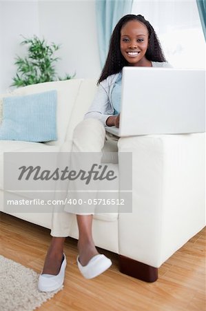 Smiling woman in the living room using her lapop