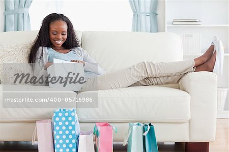 Smiling woman on couch checking her shopping