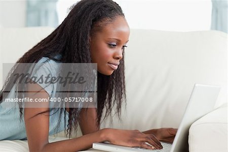 Close up of young woman lying on the sofa with her netbook