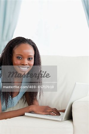 Close up of smiling woman lying on the couch with her notebook