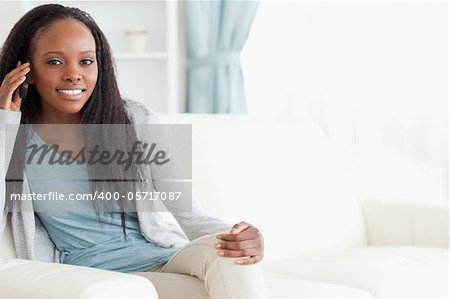 Smiling woman sitting on sofa while using her phone