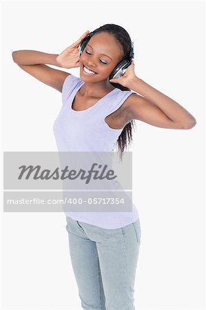 Close up of smiling woman listening to music with headphones on white background