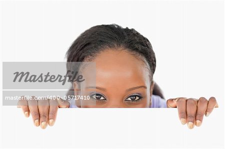 Young woman taking a look above an edge on white background