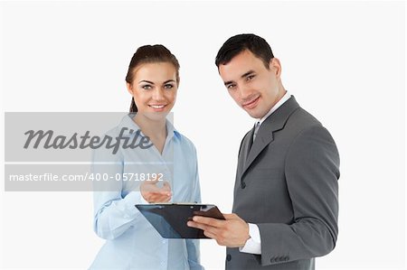 Smiling business partners with clipboard against a white background