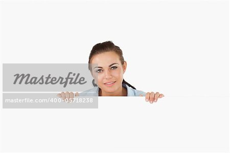 Businesswoman looking over wall against a white background