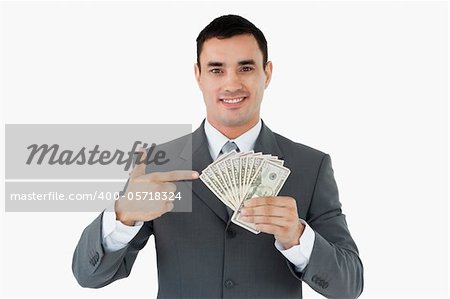 Businessman pointing at bank notes in his hand against a white background